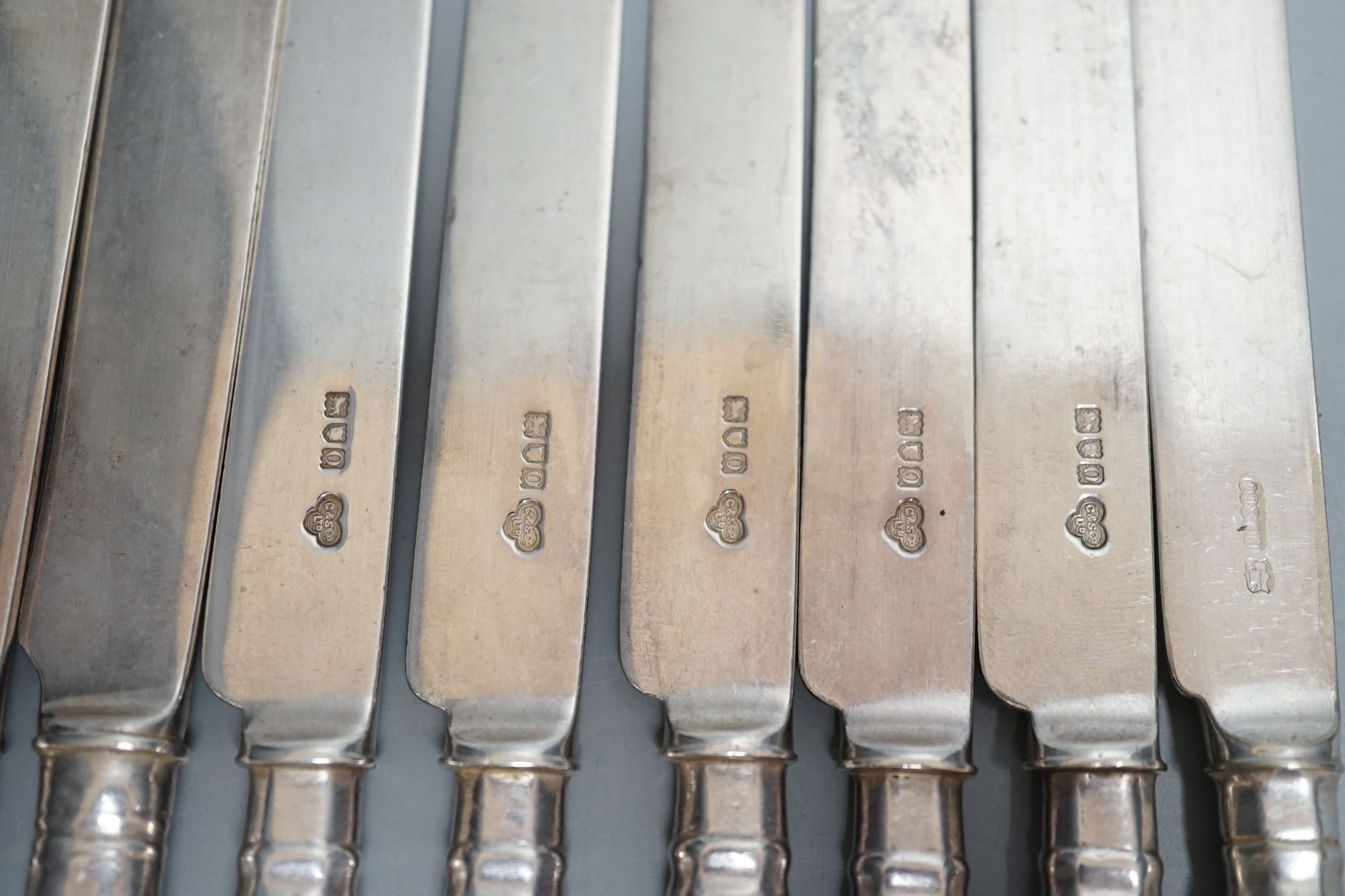 A set of seven Edwardian silver fiddle and shell pattern dessert knives, Goldsmiths & Silversmiths Co Ltd, London, 1909 and a similar plated knife.